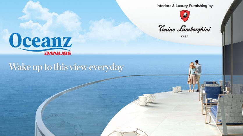 Une bannière publicitaire pour Oceanz Dubai représentant un couple debout sur un balcon surplombant la mer, avec un mobilier luxueux et le logo de Tonino Lamborghini Casa.