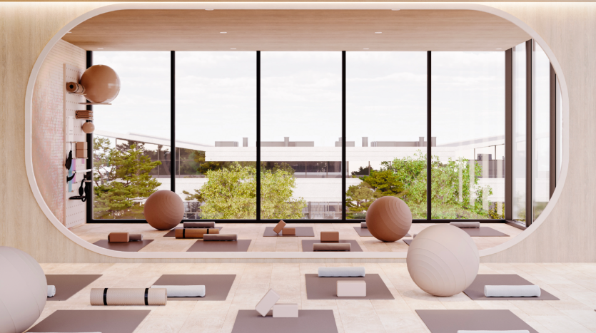 Studio de yoga moderne doté d&#039;une grande fenêtre ovale donnant sur une cour, remplie de ballons d&#039;exercice, de tapis et de blocs sur un parquet en bois. Une lumière vive et naturelle améliore l&#039;ambiance sereine, idéale pour les immobiliers recherchant