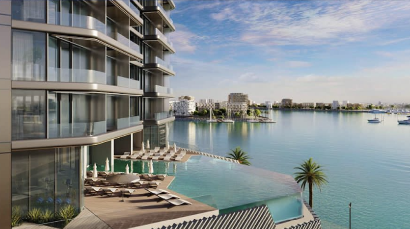 Immeuble moderne en bord de mer à Dubaï avec balcons incurvés donnant sur une marina calme bordée de palmiers et de bateaux de loisirs sous un ciel bleu clair.