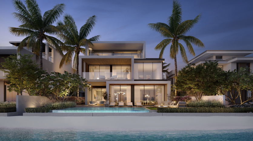 Appartement moderne et luxueux en bord de mer à Dubaï avec des intérieurs éclairés, de grands balcons et une piscine entourée de palmiers au crépuscule.