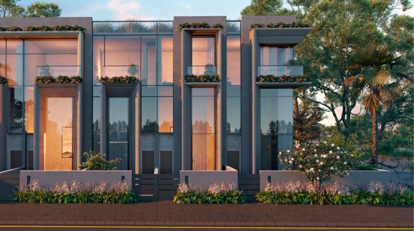 Maisons de ville modernes avec fenêtres en verre réfléchissant et jardins verticaux intégrés à la façade. Alors que le soleil couchant projette une lueur chaleureuse, mettant en valeur un aménagement paysager bien entretenu parsemé de divers arbres et buissons, cela illustre