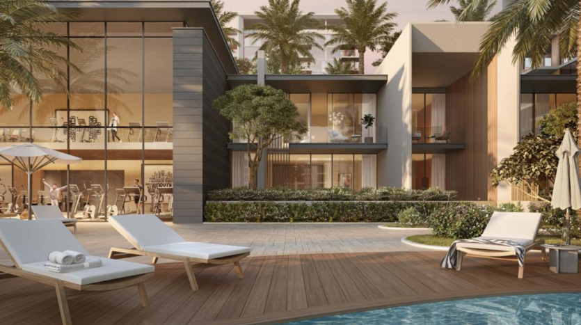 Espace luxueux au bord de la piscine avec des chaises longues blanches, entouré de bâtiments résidentiels modernes et de palmiers luxuriants à Dubaï, présentant un environnement de vie serein et haut de gamme pour un investissement immobilier potentiel.