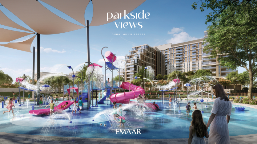 Cette image montre un parc aquatique animé dans le domaine de Dubai Hills, avec des enfants jouant sous des fontaines à jets et des zones ombragées, avec des villas modernes en arrière-plan.