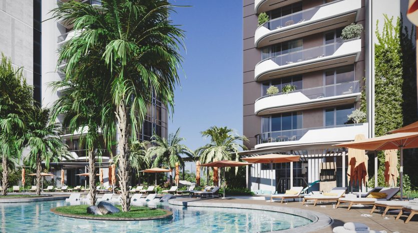 Piscine luxueuse de l'hôtel entourée de palmiers avec chaises longues et parasols, flanquée de bâtiments modernes sous un ciel bleu clair à Dubaï.