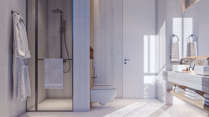Une salle de bains moderne dans une villa de Dubaï présentant un design élégant avec des murs et des surfaces en marbre, des toilettes flottantes, un espace douche ouvert et une double vasque avec des miroirs ronds. Un éclairage doux améliore l&#039;ambiance sereine