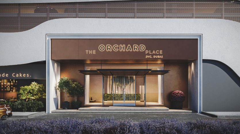 La façade de « The Orchard Place » à Dubaï présente un design moderne avec une entrée luxueuse encadrée de plantes et un éclairage élégant, adossé à un mur élégant et incurvé. Cette villa à Dubaï offre un