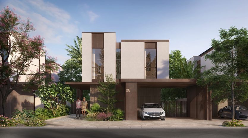 Villa moderne de deux étages à Dubaï avec un grand patio avant, présentant une conception architecturale épurée et géométrique, entourée d&#039;un aménagement paysager luxuriant. Un couple se tient à l’entrée avec des voitures garées à proximité.