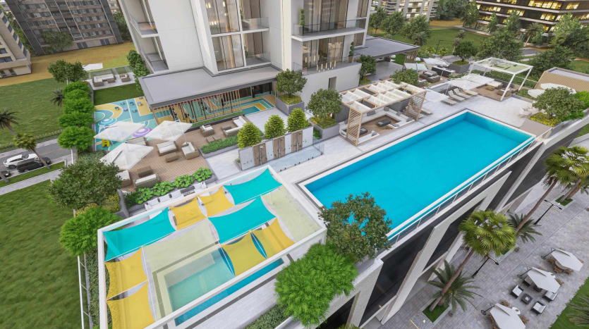Vue aérienne d&#039;une piscine moderne sur le toit flanquée de chaises longues et de jardins bien entretenus, avec une salle à manger extérieure adjacente et des bâtiments de villas résidentielles à Dubaï.