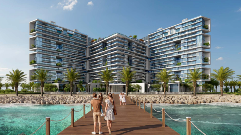 Bâtiments résidentiels modernes à plusieurs niveaux en bord de mer avec une verdure luxuriante sur les balcons sous un ciel bleu clair. Une jetée en bois avec des personnes marchant vers le complexe est visible au premier plan. Idéal pour immobilier Dubaï