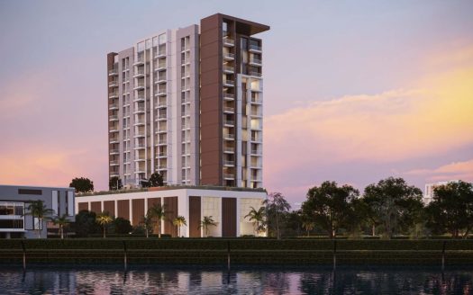 Un immeuble résidentiel moderne de grande hauteur au coucher du soleil, avec un ciel vibrant et des reflets dans un front de mer calme, entouré d&#039;une verdure luxuriante, illustre le premier immobilier de Dubaï.
