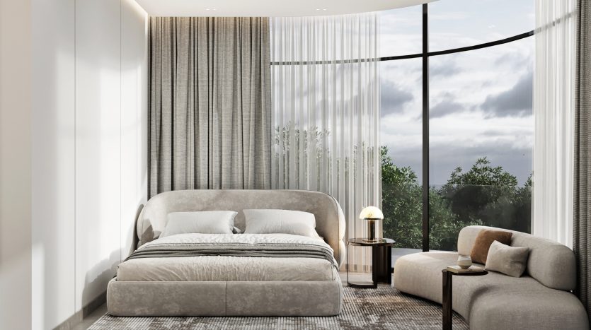Une chambre moderne et élégante dans un appartement de Dubaï comprenant un grand lit avec une literie grise et une baie vitrée incurvée révélant une vue sur la forêt. Comprend un canapé confortable, une lampe de chevet et un voilage