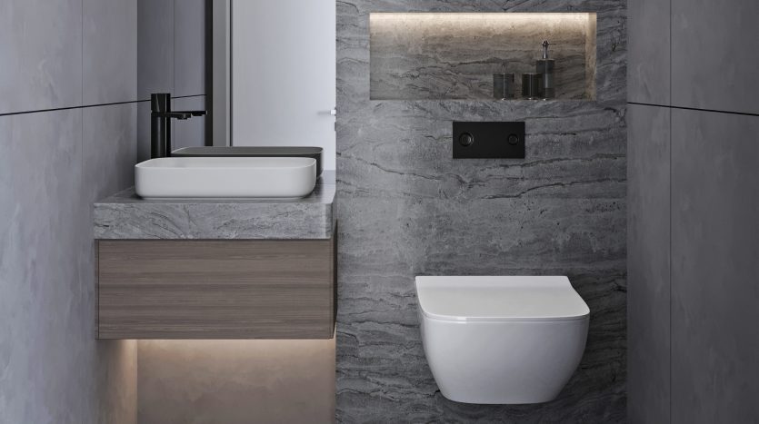 Salle de bains moderne dans une villa de Dubaï avec des murs en pierre grise, des toilettes murales et une vasque flottante avec un lavabo rectangulaire, un éclairage sous la vasque et des luminaires noirs.