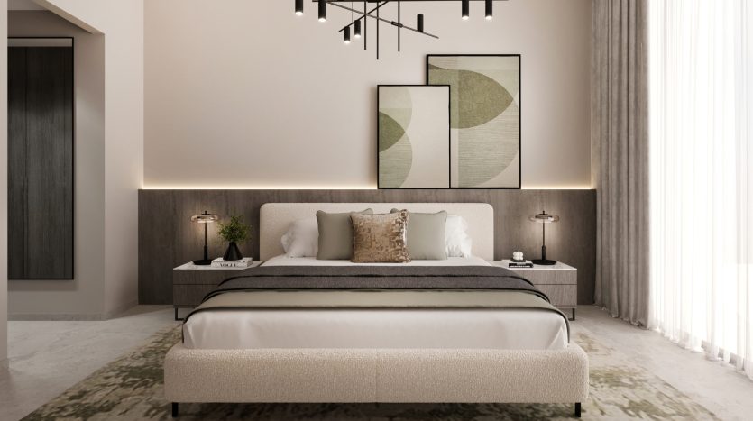 Une chambre moderne dans un appartement de Dubaï avec un grand lit doté d&#039;une literie blanche et grise, flanqué de tables d&#039;appoint et de lampes en bois, contre un mur rose clair avec des œuvres d&#039;art abstraites au-dessus de la tête de lit.