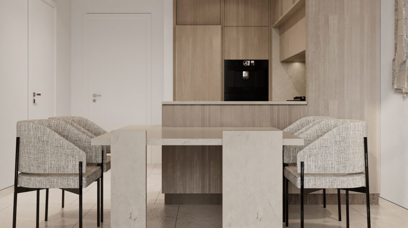 Une cuisine moderne et minimaliste dans une villa à Dubaï avec des armoires en bois élégantes, des appareils électroménagers intégrés et une table à manger en marbre flanquée de quatre chaises en tissu texturé. Une palette de couleurs neutres rehausse les lignes épurées et élégantes
