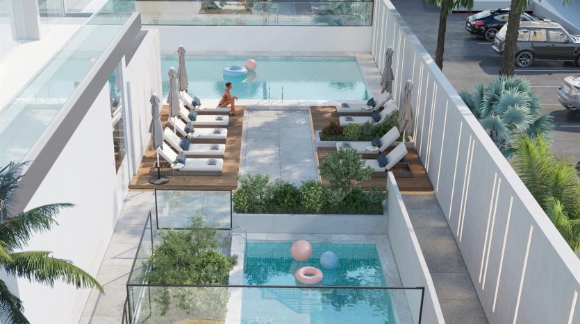 Espace luxueux au bord de la piscine dans une villa architecturale moderne à Dubaï, avec une eau bleu clair, entouré de chaises longues élégantes, avec une femme avec un chapeau assise paisiblement et des anneaux de piscine gonflables flottant à proximité
