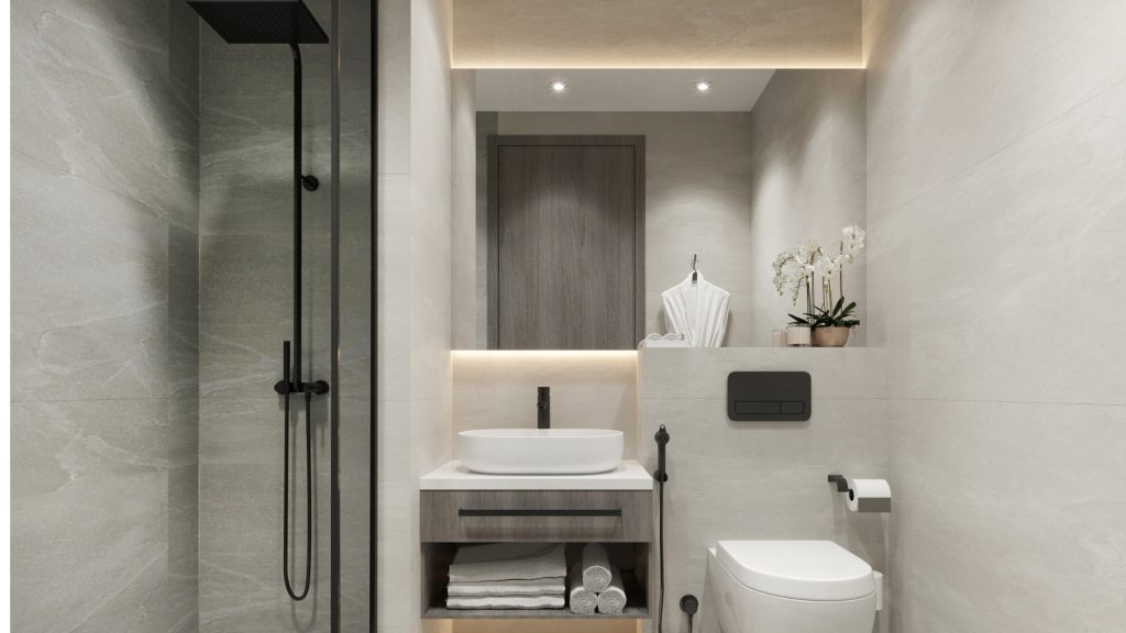 Intérieur de salle de bains moderne comprenant un meuble en bois avec un lavabo blanc, un miroir, des toilettes murales et une douche à l&#039;italienne dans un appartement de Dubaï, accentué par des carreaux de pierre grise et un éclairage chaleureux