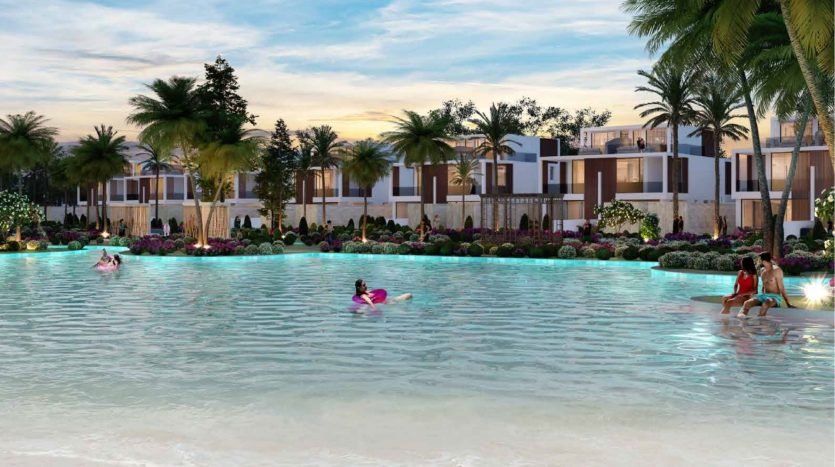 Une piscine tropicale pittoresque au crépuscule avec des gens sur des flotteurs et un couple assis au bord de la piscine, entourée de palmiers et de villas blanches modernes à Dubaï avec des jardins luxuriants.