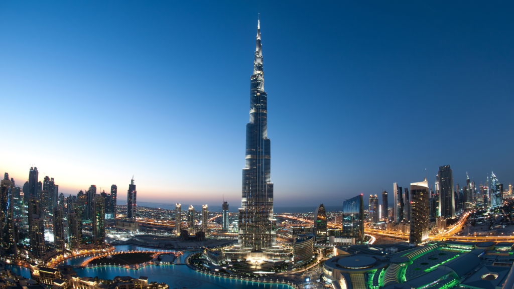 Vue panoramique de Dubaï au crépuscule avec le Burj Khalifa éclairé dominant les gratte-ciel environnants et les rues illuminées de la ville, mettant en valeur les meilleures options immobilières de Dubaï.