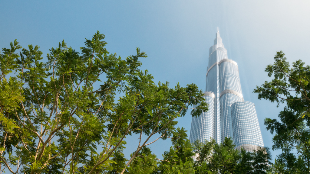 Une vue d&#039;un grand gratte-ciel chatoyant dominant des arbres verdoyants sur un ciel bleu clair, incarnant le premier immobilier de Dubaï.