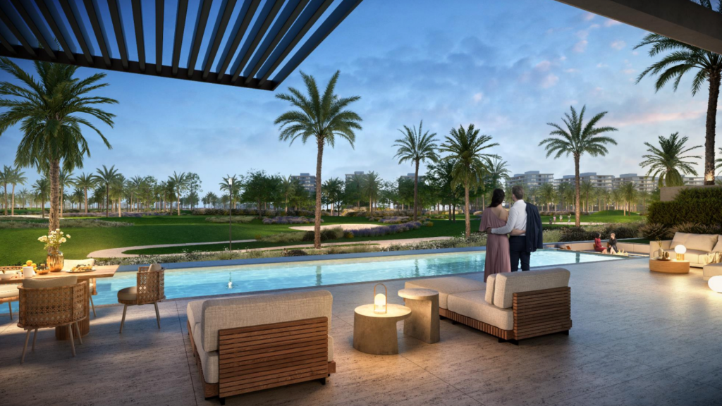 Un couple se tient sous un pavillon ombragé surplombant une piscine luxueuse et des jardins luxuriants au crépuscule, avec des sièges extérieurs confortables à proximité, mettant en valeur les normes exceptionnelles de l'appartement Dubaï.
