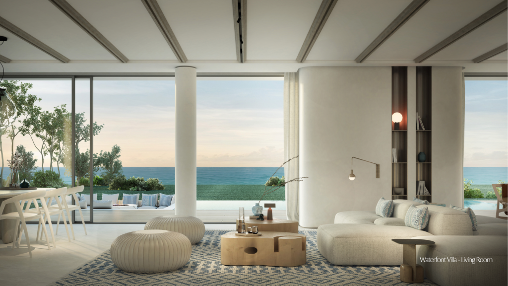 Une luxueuse villa en bord de mer à Dubaï avec une décoration moderne, comprenant un canapé et un fauteuil, donnant sur une vue panoramique sur l'océan grâce à de grandes portes coulissantes ouvertes.