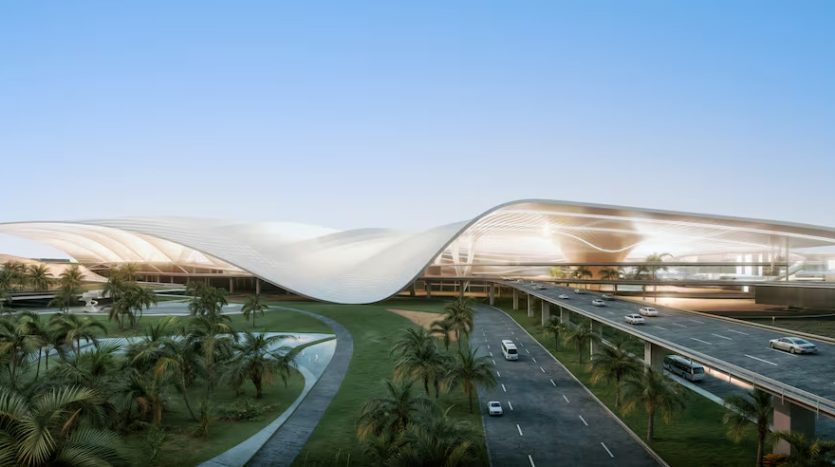 Une image d’un terminal d’aéroport moderne et futuriste avec un toit élégant en forme de vague. Il est entouré de palmiers luxuriants avec des voitures sur une route voisine sous un ciel clair au crépuscule, à proximité de projets immobiliers importants à Dubaï.