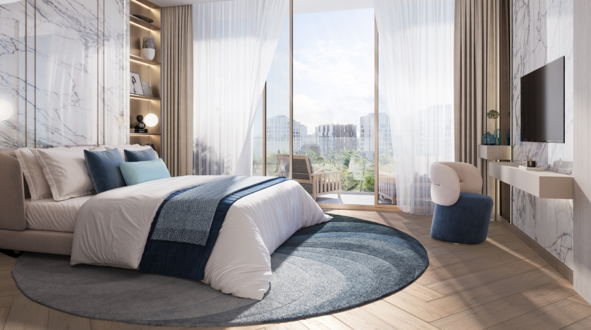 Chambre moderne avec un grand lit, une literie bleue et blanche et un tapis rond gris-bleu. La fenêtre du sol au plafond avec des rideaux transparents révèle un balcon et un paysage urbain. Une télévision accrochée au mur, des étagères intégrées et une chaise moelleuse complètent la pièce. Un éclairage doux crée une ambiance chaleureuse qui rappelle les soirées agréables après une promenade tranquille sur la plage.