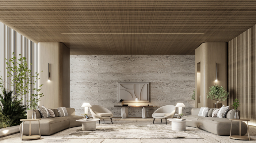 Un salon luxueux et moderne des résidences Azura présente un design minimaliste avec un plafond en bois, des murs en pierre texturée et un sol en pierre de couleur claire. L'espace comprend deux grands canapés beiges, des tables rondes, des plantes en pot et des œuvres d'art murales contemporaines.