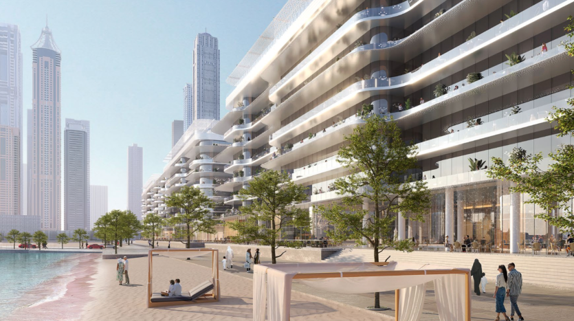 Un bâtiment résidentiel moderne en bord de mer avec plusieurs balcons, palmiers et coins salons extérieurs orne le paysage des Dubai Harbour Residences. Les gens se promènent le long de la plage de sable tandis que d’autres se détendent sous les auvents ombragés. Les gratte-ciel s'élèvent majestueusement en arrière-plan sous un ciel bleu clair.