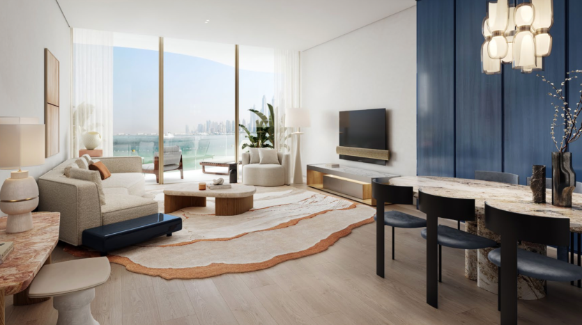 Salon et salle à manger sophistiqués des Dubai Harbour Residences avec un mobilier moderne. Les caractéristiques comprennent une grande fenêtre avec vue sur la ville et l'eau, un canapé blanc, une table à manger en marbre et une télévision murale. Des tons neutres, des tapis texturés et des rideaux bleus rehaussent le décor.