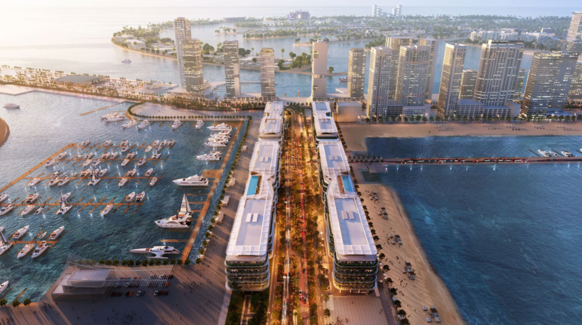 Une vue aérienne des Dubai Harbour Residences révèle une ville côtière moderne avec des immeubles de grande hauteur, une zone en bord de mer et une marina remplie de yachts. Une promenade centrale éclairée traverse le milieu, bordée d'arbres et de bâtiments. Les cours d'eau et les espaces verts sont visibles en arrière-plan.