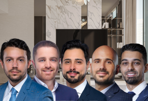 Cinq hommes en tenue professionnelle se tiennent dans un bureau moderne et haut de gamme de Dubai Immo, doté de murs en marbre et de grandes fenêtres. Ils regardent tous la caméra et sourient.