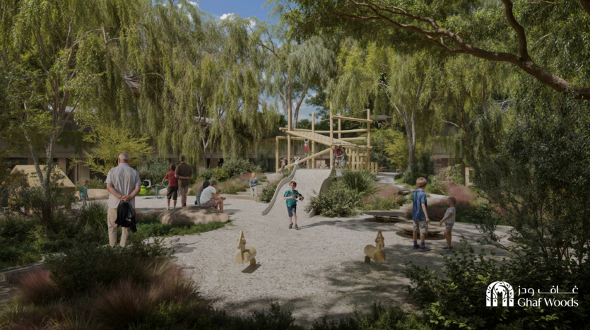 Un parc communautaire pittoresque, Ghaf Woods, dispose d'une aire de jeux avec des enfants et des adultes participant à diverses activités. La zone est luxuriante de verdure, comprenant de grands arbres et des buissons. Au premier plan, des bancs et des balançoires sont visibles. Le panneau « Ghaf Woods » est placé bien en évidence dans le coin inférieur droit.