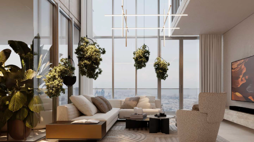 Un salon moderne avec de grandes fenêtres offrant une vue sur la ville dans un appartement de Dubaï, comprenant des plantes vertes suspendues, un ensemble de canapés beige, une télévision murale et une élégante suspension.