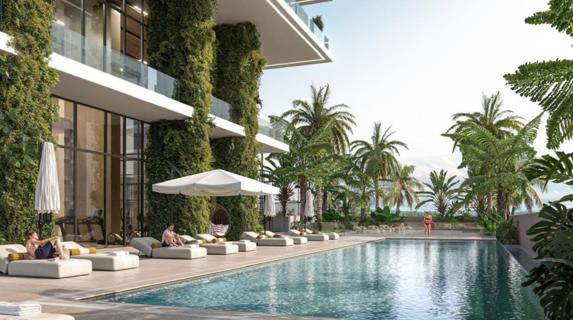 Espace piscine luxueux de la marina moderne de Kempinski Dubaï, avec chaises longues, verdure luxuriante et océan en arrière-plan, permettant aux clients de se détendre et de profiter du cadre tranquille.