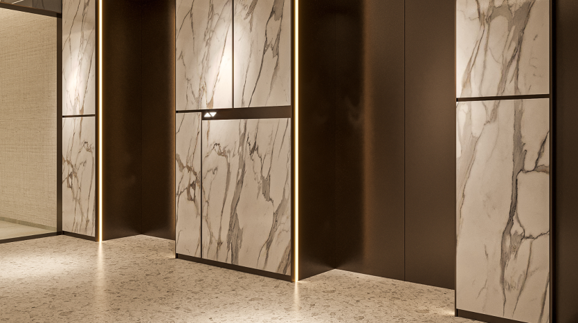 Vue intérieure d&#039;un cadre moderne des Primero Residences Al Furjan comprenant des armoires hautes avec une finition en marbre et un éclairage ambiant chaleureux. Le sol est constitué d’un matériau légèrement moucheté, renforçant l’esthétique minimaliste et raffinée de l’espace.
