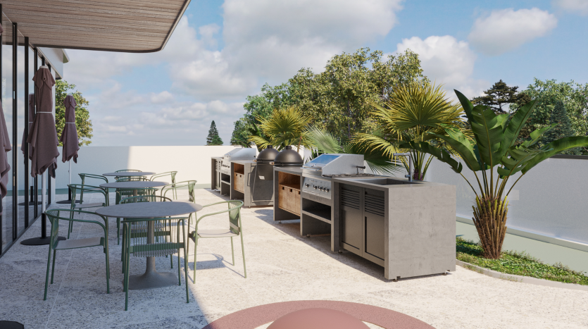 Le patio extérieur moderne du Primero Residences Al Furjan comprend plusieurs barbecues en métal et en béton, quelques tables rondes avec des chaises vertes et est entouré de verdure luxuriante et de palmiers. La zone est sous un ciel clair et ensoleillé, créant une atmosphère invitante pour cuisiner et manger en plein air.