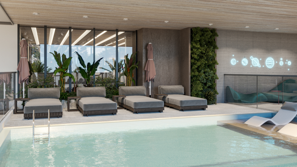 La piscine intérieure du Primero Residences Al Furjan comprend des chaises longues modernes alignées le long du bord, certaines avec des parasols. Des plantes vertes et un mur de jardin vertical ajoutent une touche de nature. Les grandes fenêtres apportent de la lumière naturelle, tandis que les néons contribuent à l&#039;ambiance sereine.