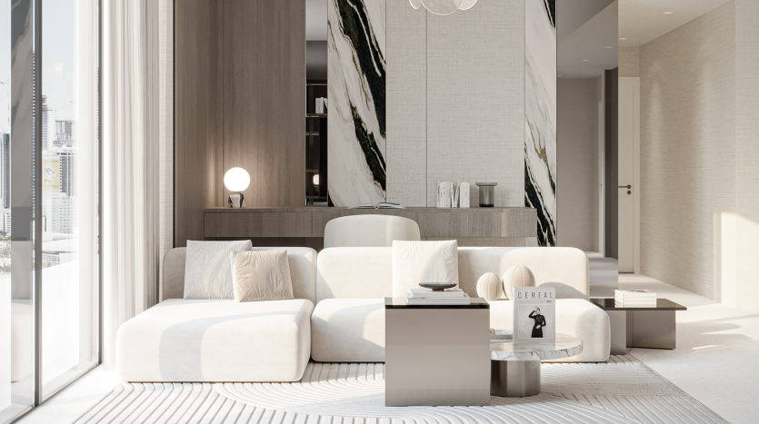 Un salon moderne et minimaliste du Primero Residences Al Furjan comprend un canapé sectionnel blanc, un tapis de couleur claire et des tables basses élégantes. Un mur d&#039;accent en marbre avec un motif géométrique ajoute de la sophistication, tandis qu&#039;une baie vitrée inonde l&#039;espace de lumière naturelle.