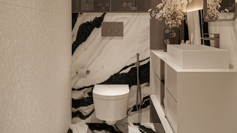 Une salle de bains moderne du Primero Residences Al Furjan comprend des toilettes murales avec une plaque à double chasse au-dessus. Les murs et le sol sont finis avec un superbe motif de marbre noir et blanc. Il y a une vanité blanche et élégante avec un lavabo rectangulaire et un robinet haut.