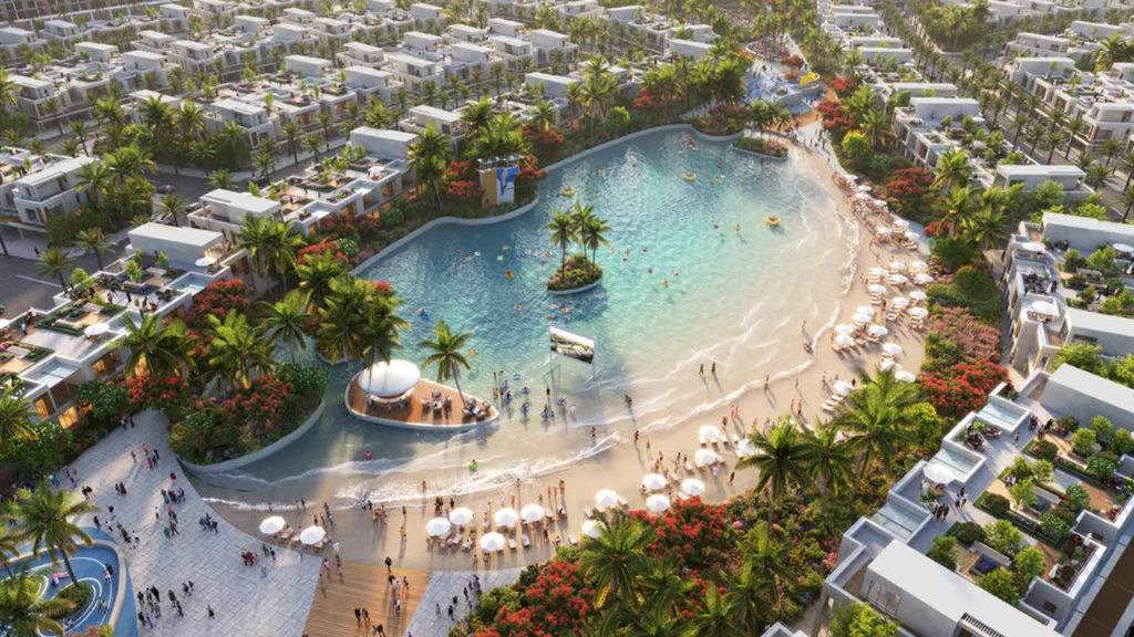 Vista aerea di un complesso di lusso con una grande piscina in stile laguna circondata da una rigogliosa vegetazione tropicale e numerose ville bianche sotto un cielo soleggiato nel sud di Dubai.