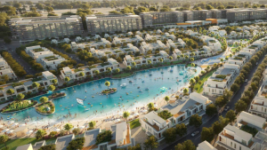 Vue aérienne d'un quartier résidentiel moderne du sud de Dubaï comprenant un grand lac artificiel central, entouré de bâtiments blancs et d'une verdure luxuriante, avec des gens pratiquant diverses activités nautiques.