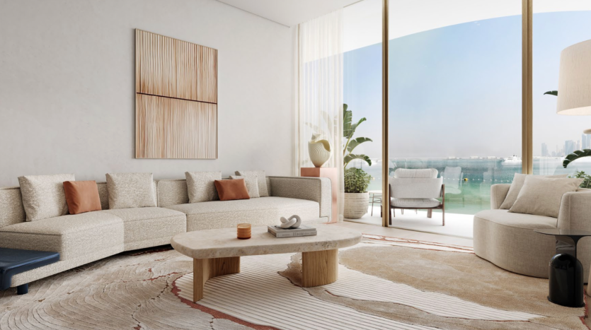 Un salon moderne des Dubai Harbour Residences avec de grandes fenêtres donnant sur le front de mer. Il comprend un canapé sectionnel beige clair avec des coussins de couleur rouille, un fauteuil rond, une table basse en bois, des œuvres d'art murales abstraites, des plantes en pot et un tapis aux tons neutres avec un motif ondulé.