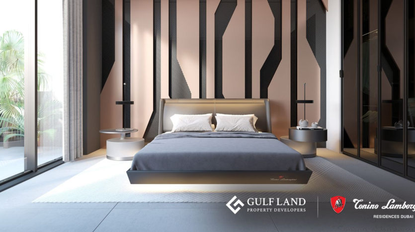 Chambre moderne au design épuré. La chambre comprend un grand lit avec une tête de lit grise contre un mur à motifs géométriques. Des tables de nuit avec lampes se trouvent de chaque côté. Les fenêtres du sol au plafond laissent entrer la lumière naturelle et les logos de Gulf Land et Tonino Lamborghini Residences Dubai sont visibles.