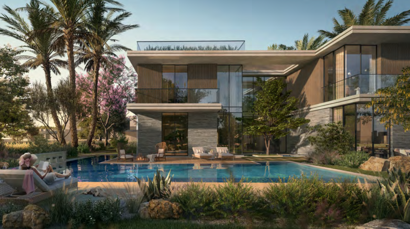 Une villa moderne de deux étages avec de grandes fenêtres vitrées, entourée de jardins luxuriants et de palmiers. Une femme se détend au bord de la piscine qui reflète le ciel bleu clair.