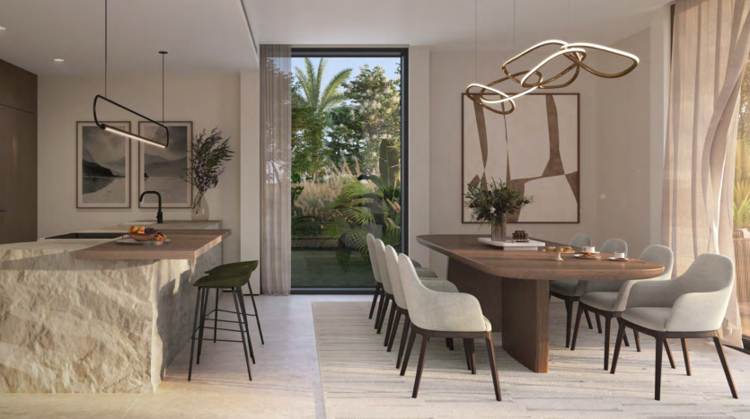 Une salle à manger moderne dans une villa avec une table ovale en bois entourée de chaises grises, adjacente à une cuisine avec un îlot en marbre et des tabourets de bar. De grandes fenêtres affichent un jardin luxuriant. Luminaires dorés élégants