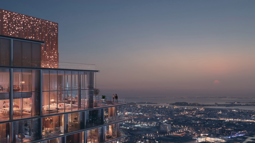 Une vue nocturne du paysage urbain depuis un grand bâtiment moderne avec des fenêtres éclairées dégage une impression de verve. Deux niveaux de balcon visibles ornés de lumières surplombent une zone urbaine tentaculaire en contrebas et un horizon lointain, avec un soleil rose se couchant sur un ciel passant du crépuscule à la nuit.