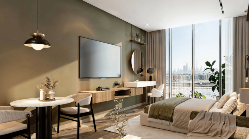 Un studio moderne et confortable avec une grande fenêtre offrant une vue sur le paysage urbain, à quelques pas des jardins Ayana. L'espace comprend un lit, une table à manger avec des chaises, une télévision murale, des étagères et une coiffeuse. La pièce présente des tons neutres, des accents verts et une lumière naturelle abondante.