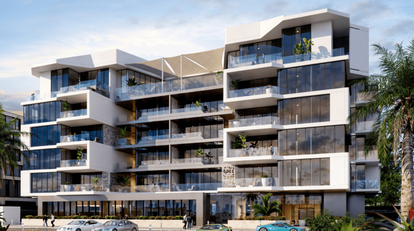 Un immeuble d'appartements moderne à plusieurs étages avec de grandes fenêtres et balcons. La façade présente un mélange de panneaux blancs et de verre avec des éléments de design minimalistes. Certains balcons ont de la verdure, renforçant l'ambiance des jardins Ayana. Plusieurs voitures garées et des palmiers sont au premier plan.