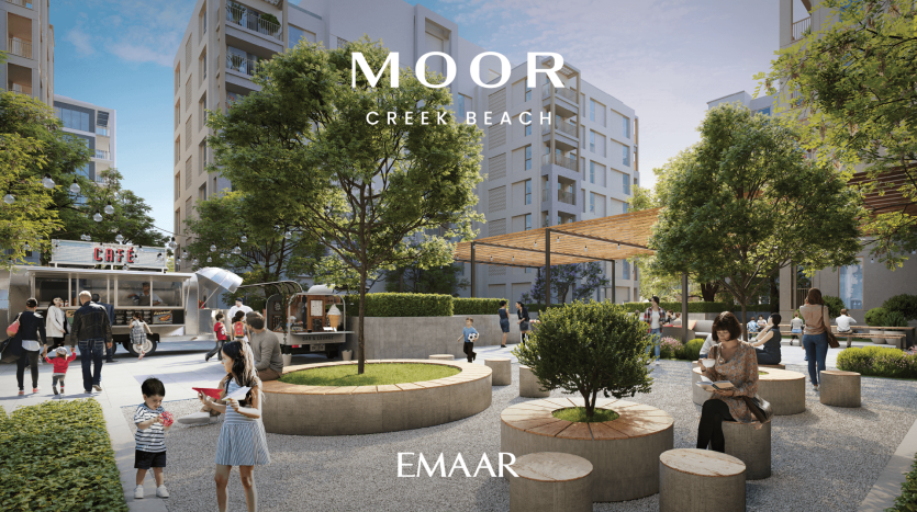 Une cour dans un quartier résidentiel moderne avec de la verdure, des bancs et des gens qui se détendent. Un café est visible en arrière-plan. Le texte sur l’image indique « Moor Creek Beach » et « EMAAR.